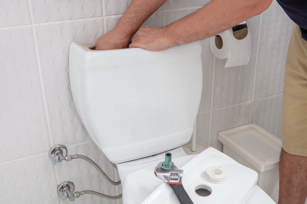 Man using hands repairing toilet cistern