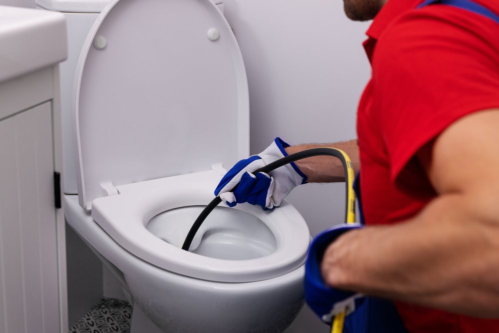 plumber unclogging blocked toilet with hydro jetting at home bat